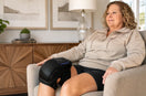 Adult using the FORTHiQ Knee Massager Pro+ during a calm seated vibration routine